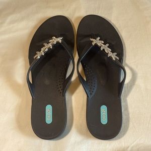 Size 11 black woman’s flip flops with star fish on them.